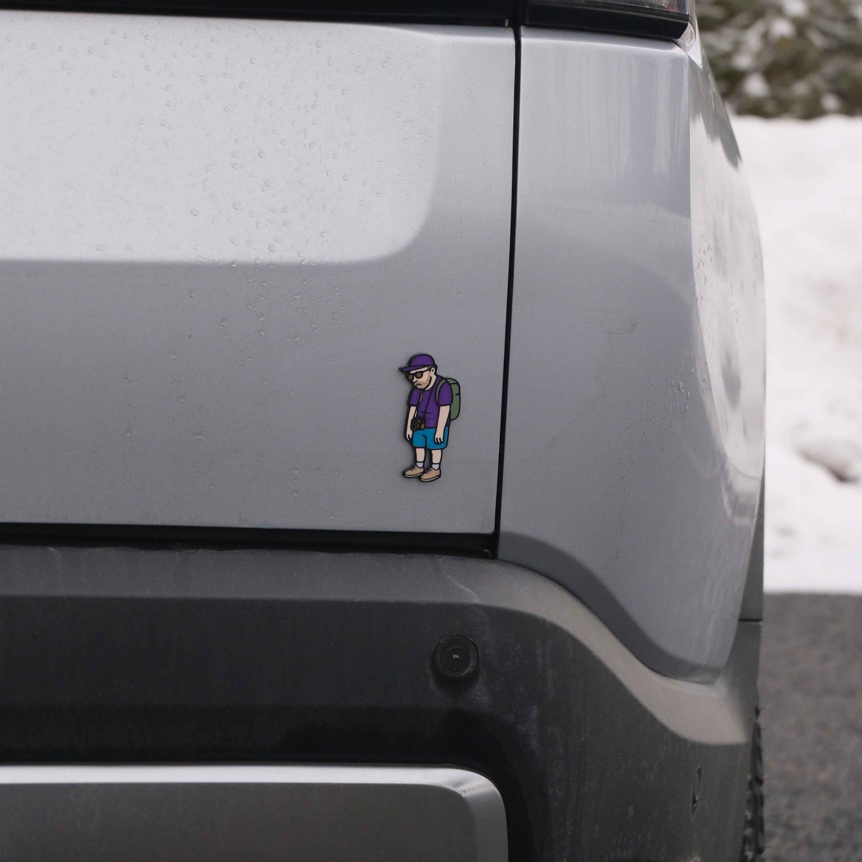 Sticker of a person with a backpack on the side of a vehicle in a snowy landscape